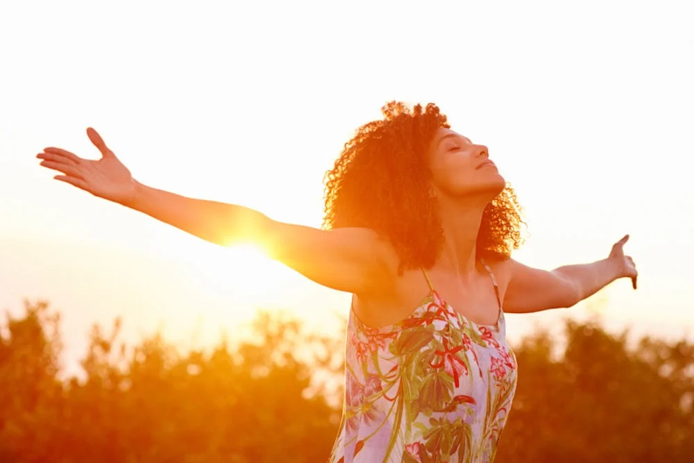 a woman with arms stretched out in sunlight