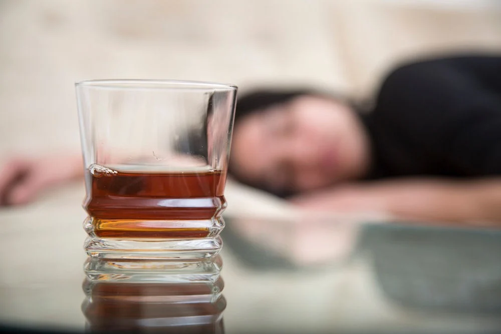 a woman laying down with whiskey on table