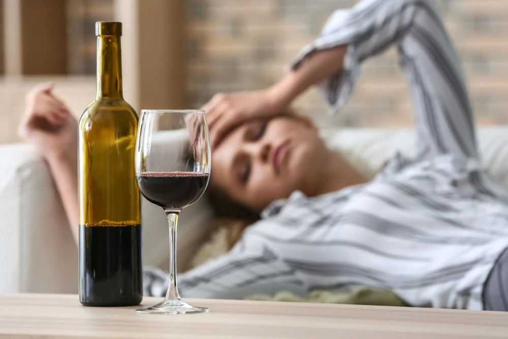 a woman with hands on head and wine on table
