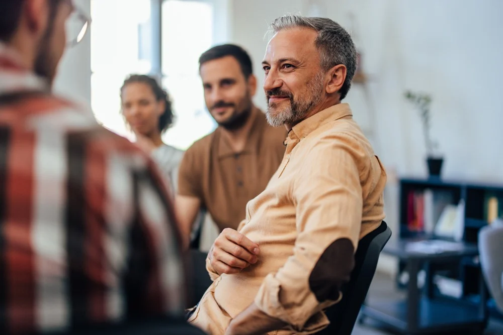 a man smiling at instructor in group therapy