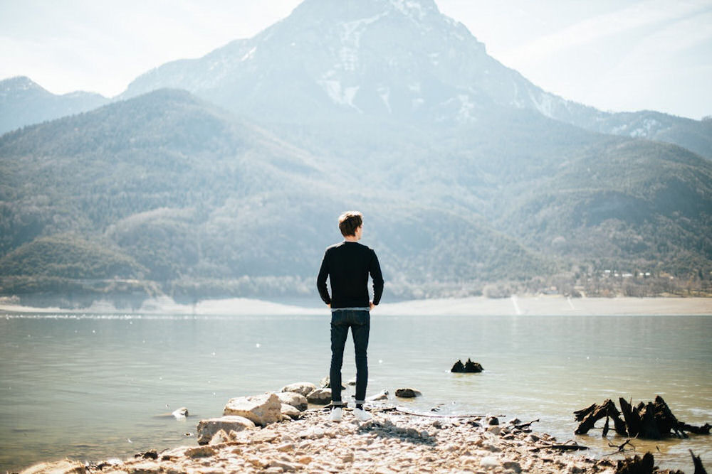 a-man-standing-on-the-beach-looking-out-to-the-moutains