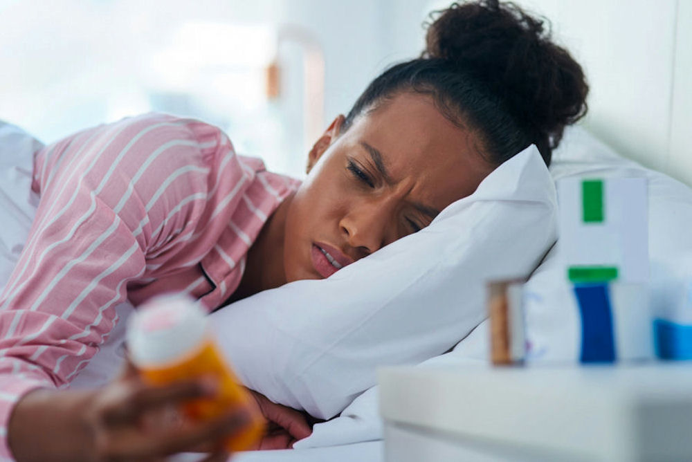 a-woman-laying-down-holding-a-bottle-of-pills