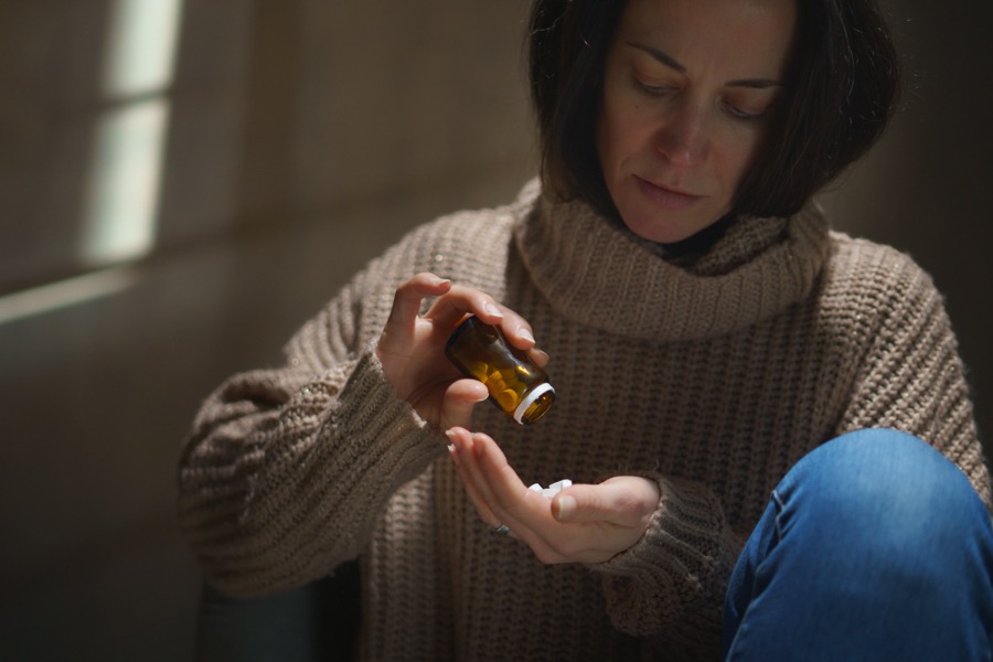 a-woman-pouring-pills-in-hand-self-medicating