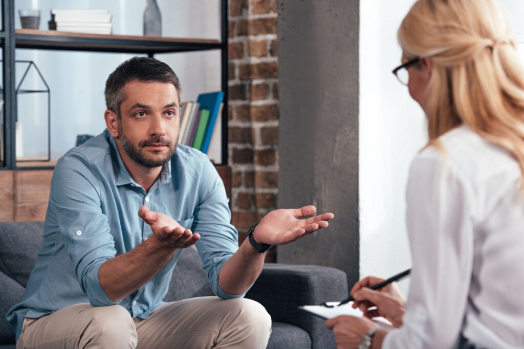 man with hands raised in therapy