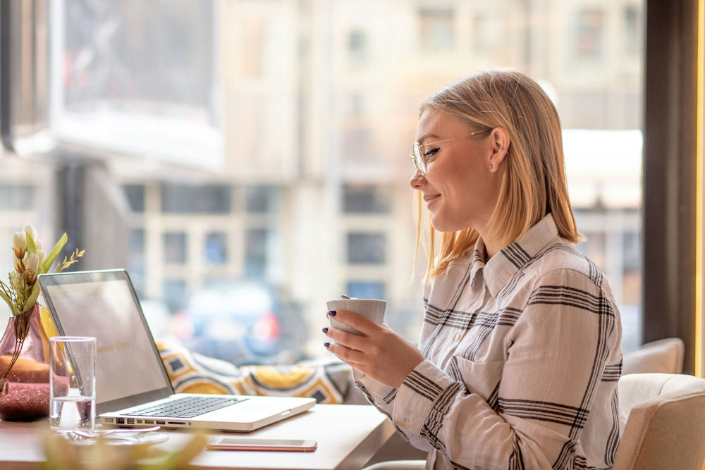 happy woman sitting at computer looking at rehab financial assistance