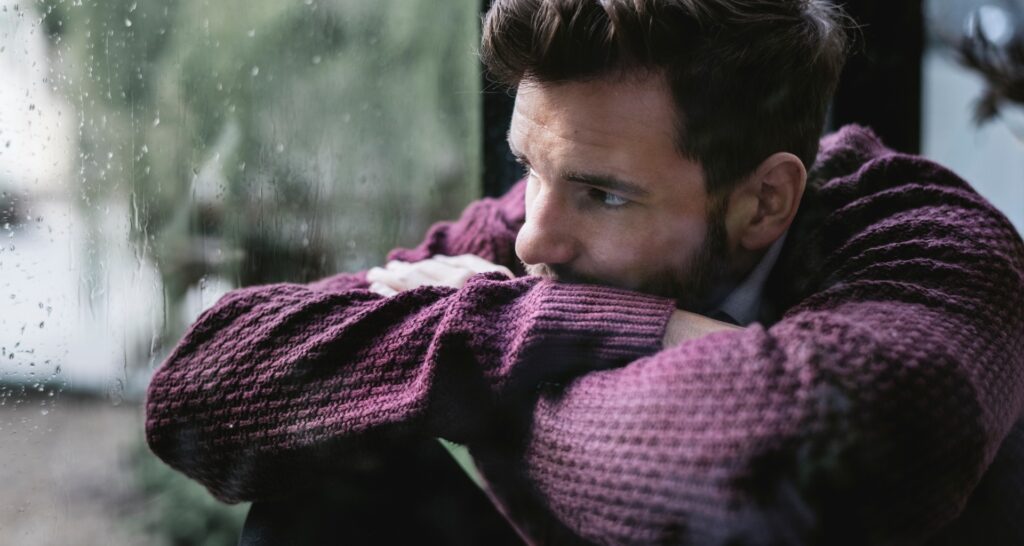 a man staring out the window sad
