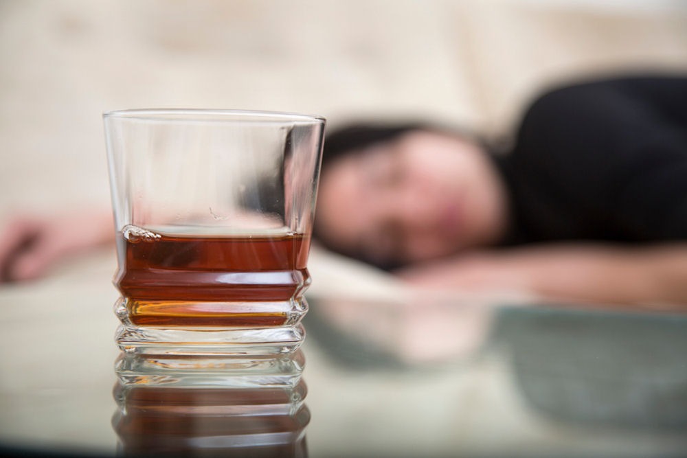 a woman laying down with whiskey on table