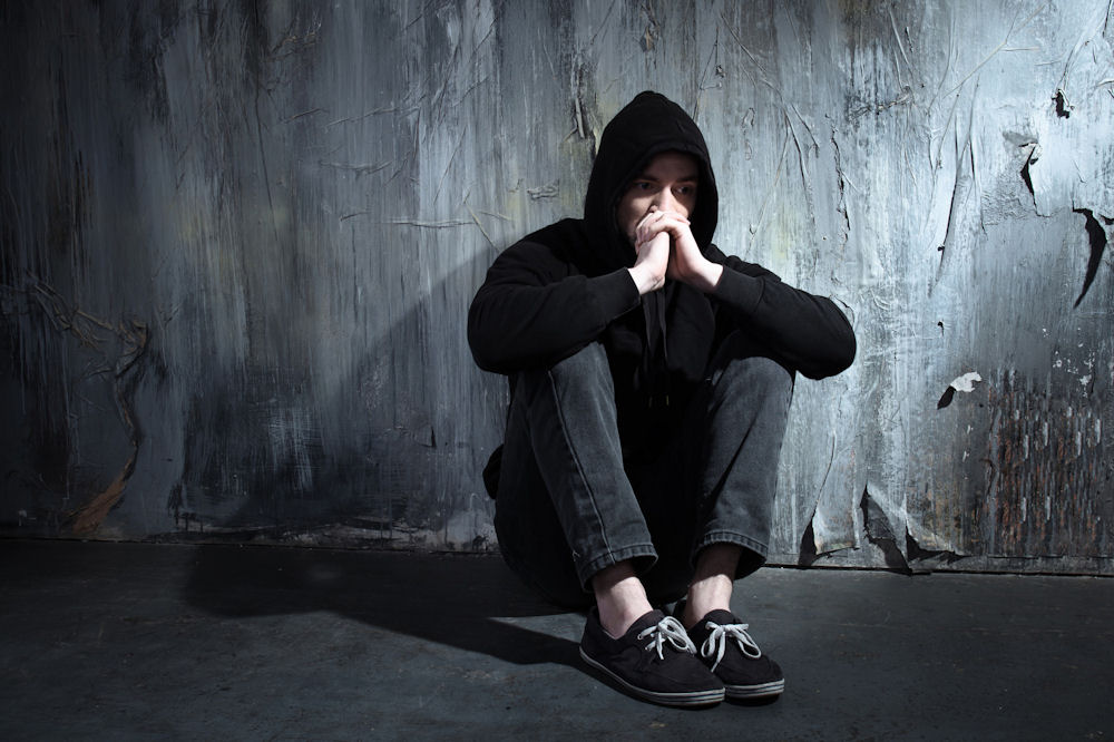 a man with his hands together sitting down sad