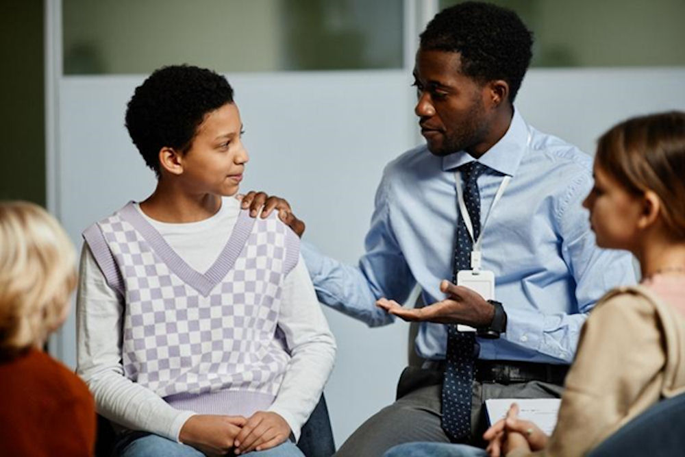Therapist supporting a young client during a stimulant rehab group session.