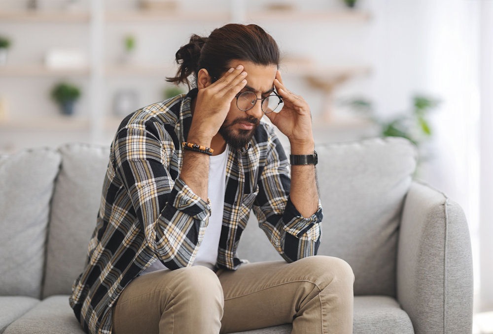Distressed man holding head in hands, possibly questioning if Adderall can help with anxiety