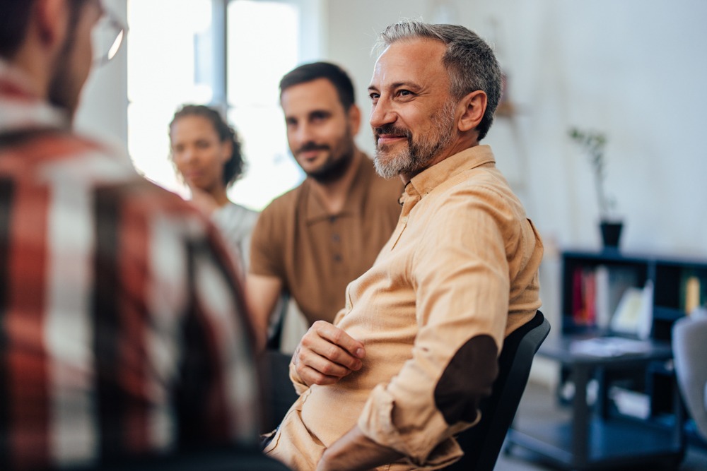 a man smiling at instructor in group therapy