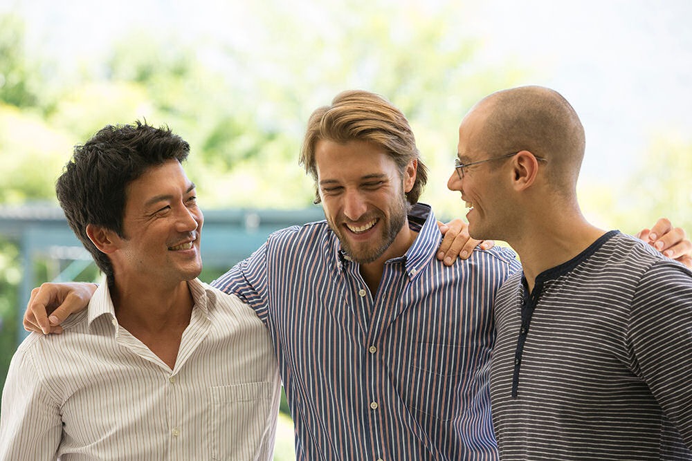 A group of men smiling and supporting each other, embracing the benefits of being sober.