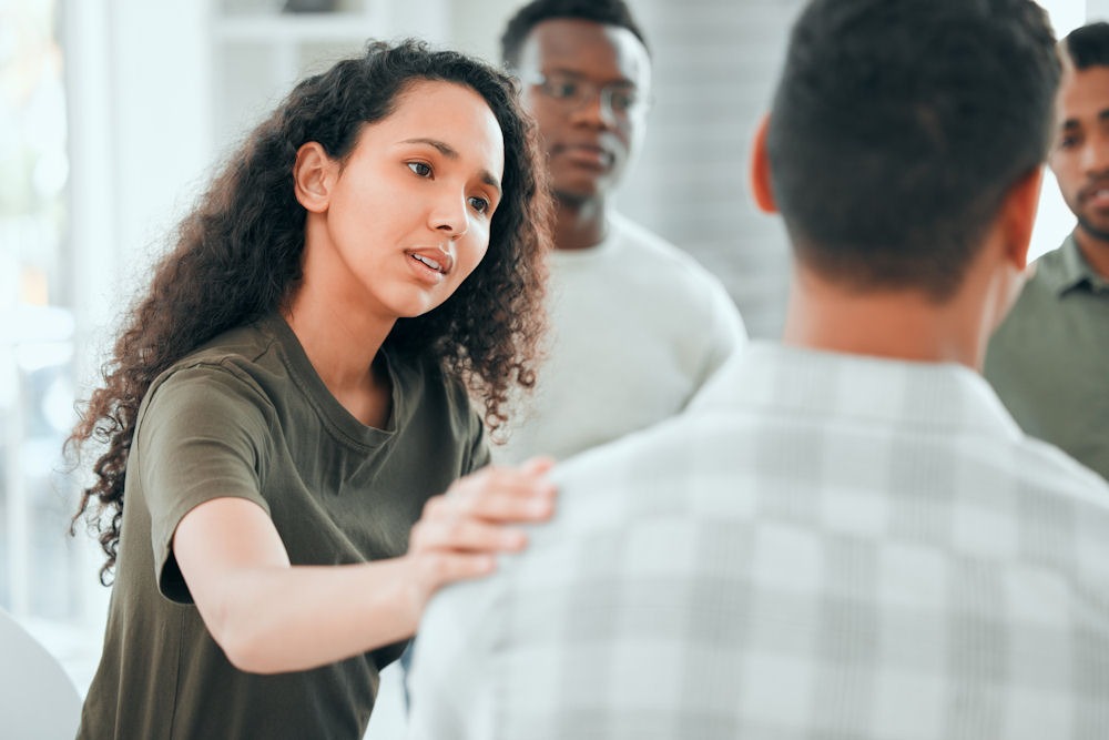 a woman comforting a man in group therapy
