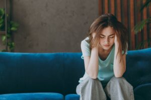 Young woman sitting on a couch looking distressed, representing emotional struggles during cocaine rehab