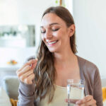 a woman smiling taking a pill