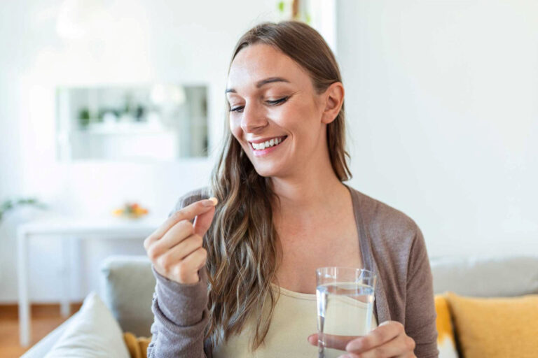 a woman smiling taking a pill